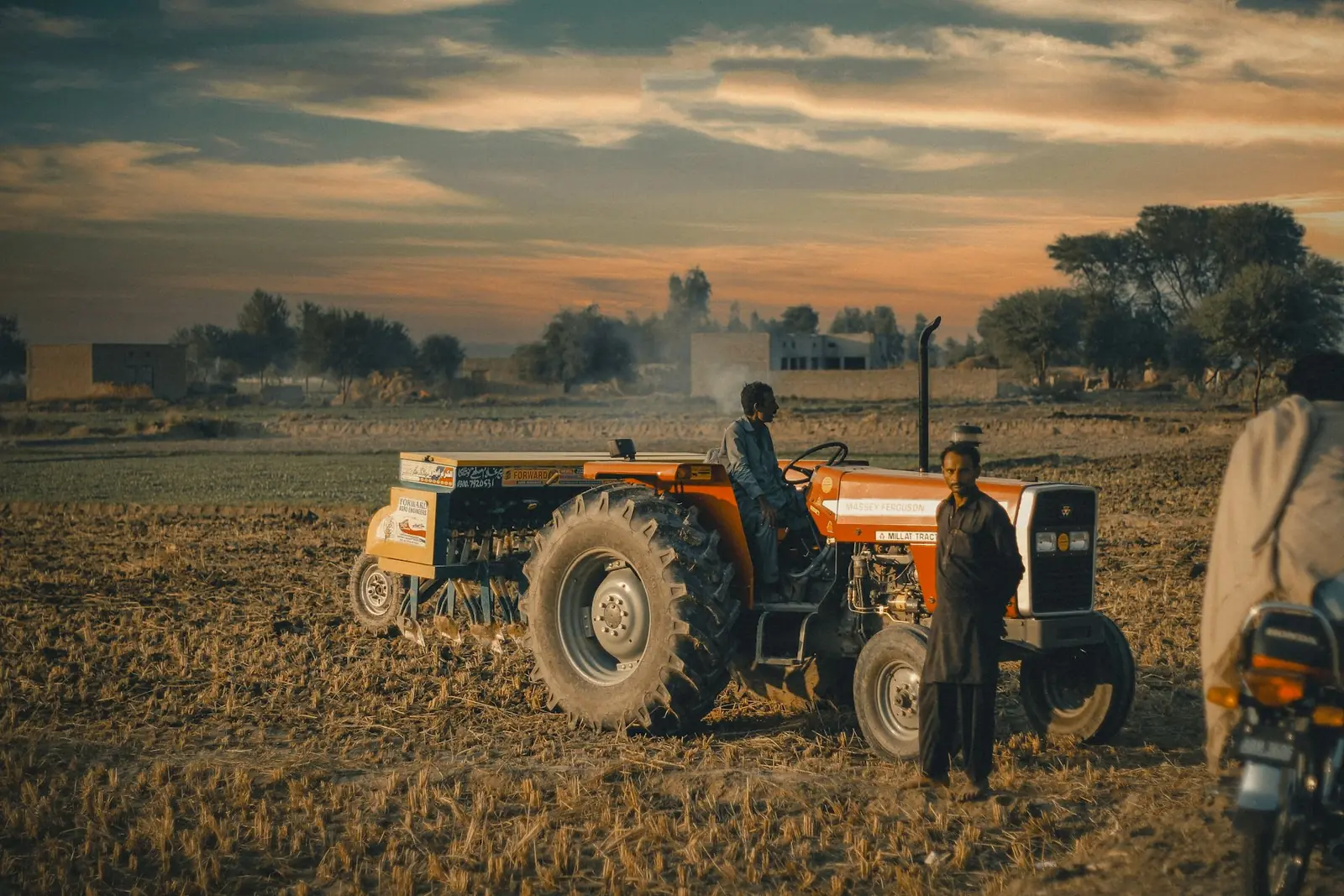 Farmers with a tractor preparing a field in Pakistan at sunset